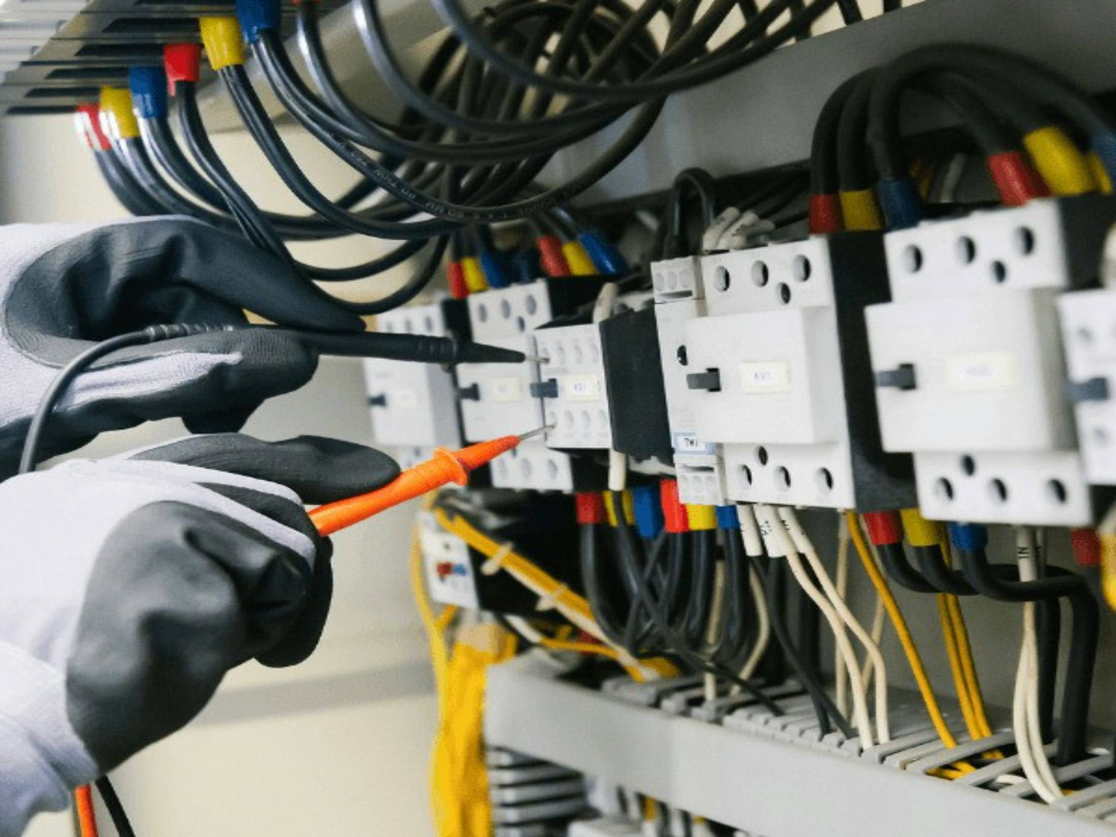 Electrician testing contactors in a control panel