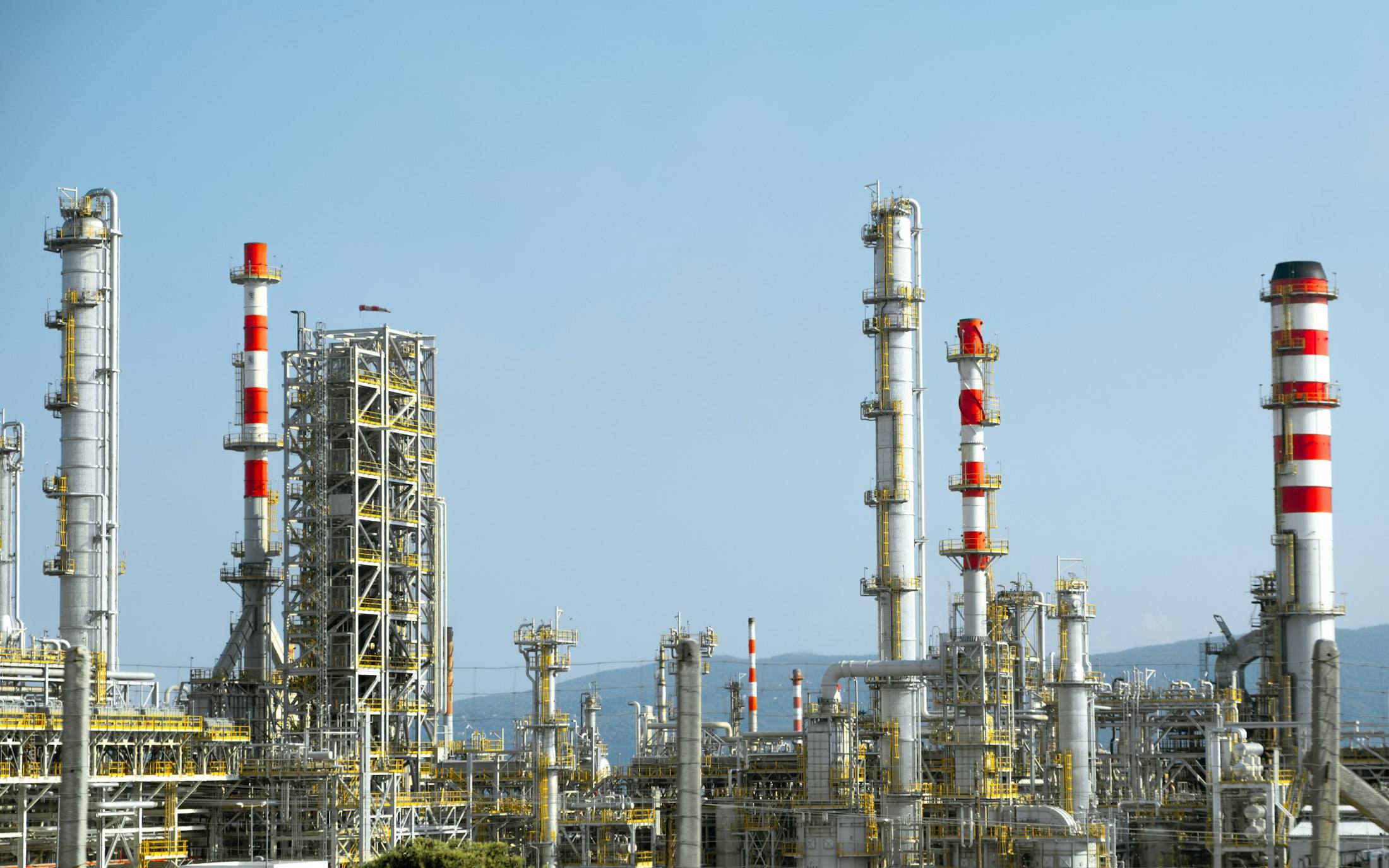 Oil and gas refinery towers and pipework under a blue sky